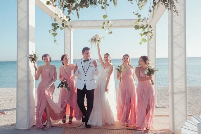 New Zealand newlywed couple posing with four bridesmaids in pink dresses