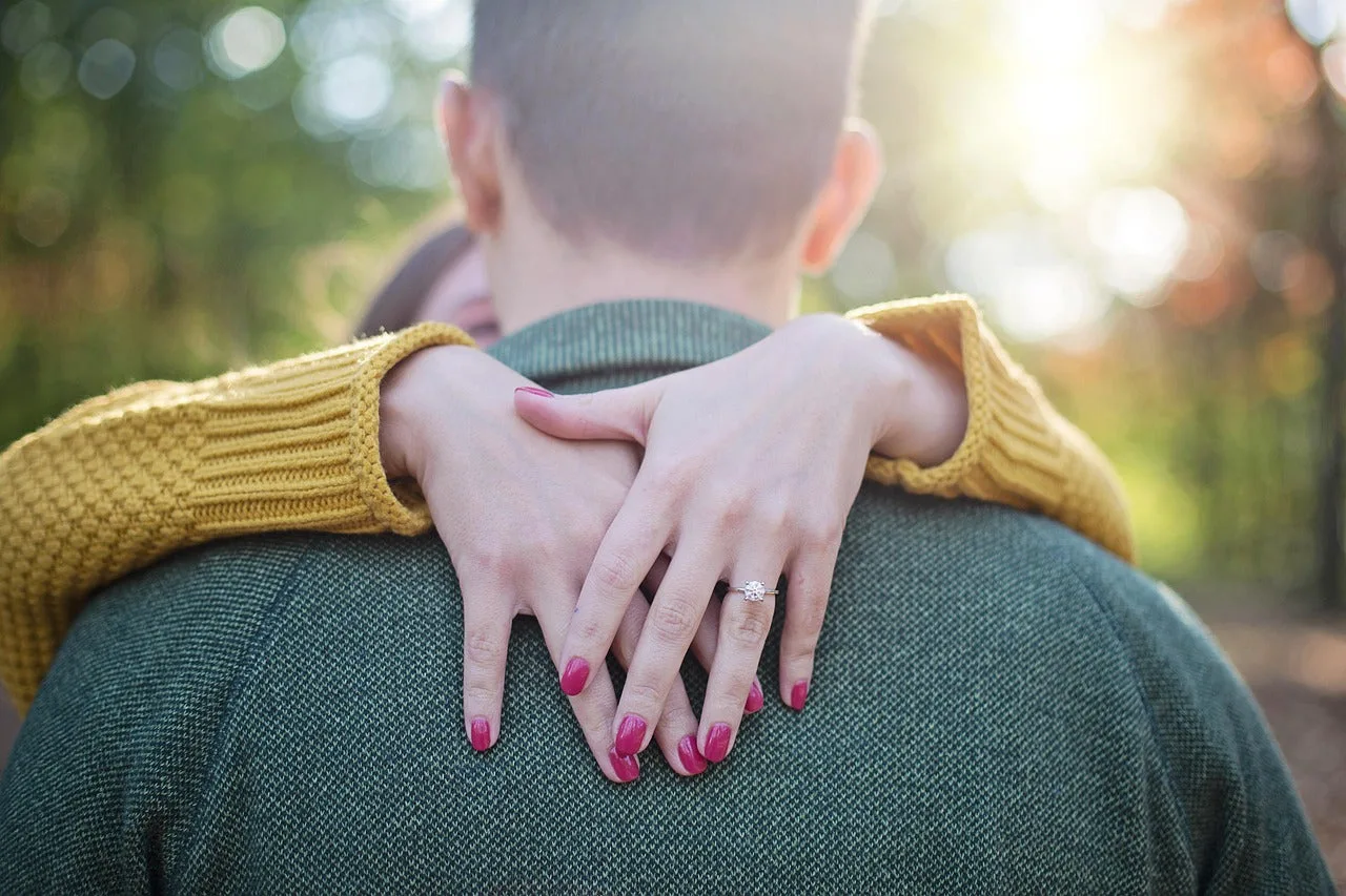 Newly engaged Australian couple with the bride-to-be hugging her fiancé from behind